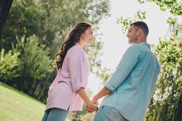 Photo of two peaceful idyllic people hold arms look each other enjoy warn nice weather outdoors.