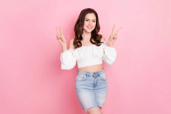 Photo of young adorable stunning young girl showing v-sign wear cute blouse and sexy skirt isolated on pink color background.