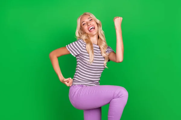 Portrait of astonished satisfied person raise fists scream yeah hooray isolated on green color background.