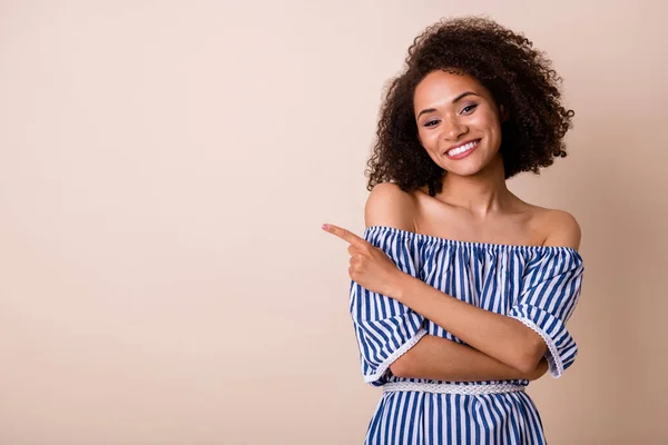 Portrait of stunning cute girl toothy smile direct finger empty space isolated on beige color background.