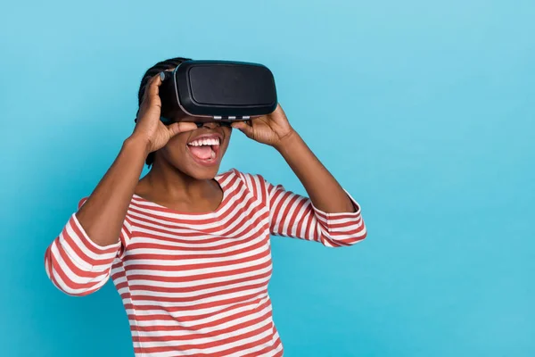 Portrait of excited crazy person hands touch vr glasses open mouth isolated on blue color background.