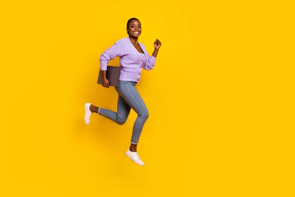 Full body profile photo of crazy carefree girl jump rush fast empty space hold netbook isolated on yellow color background.