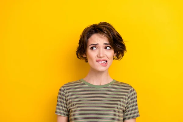 Closeup photo of unsure attractive girl looking empty space bit lip oops isolated on bright yellow color background.