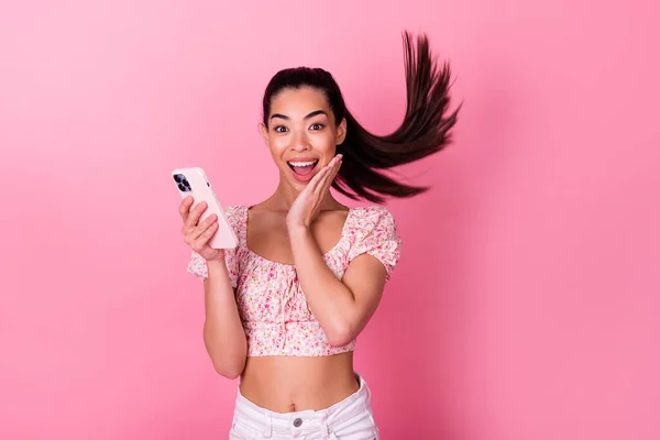 Portrait of astonished funny person hand touch cheek hold telephone isolated on pink color background.