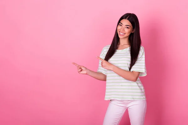 Portrait of adorable satisfied thai person indicate fingers empty space promotion isolated on pink color background.