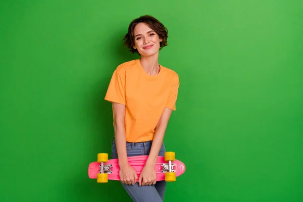 Portrait of nice satisfied person arms hold skate board enjoy pastime isolated on green color background.