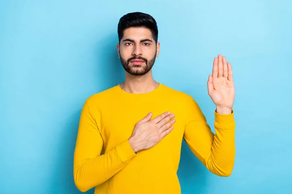 Photo of serious confident man wear yellow sweater promising tell truth isolated blue color background.