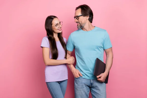 Photo of two idyllic lovely business people hold hand look each other isolated on pink color background.