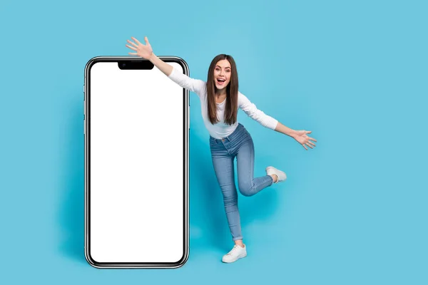 Photo of excited funky lady dressed white shirt arms sides modern device empty space isolated blue color background.