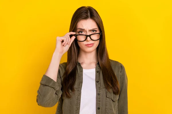 Photo of clever serious businesswoman look at you with judging expression isolated on yellow color background.