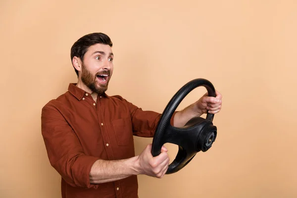 Photo of impressed funny person hold wheel look empty space open mouth isolated on beige color background.