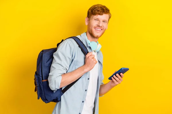 Photo of cheerful positive funny boy hand arm hold telephone backpack ready learning empty space isolated on yellow color background.