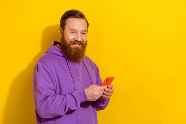 Photo of cool positive guy dressed purple sweater chatting modern gadget empty space isolated yellow color background.
