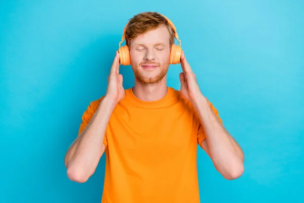 Photo Attractive Guy Wear Orange Outfit Arms Touch Headphones Closed — Fotografia de Stock