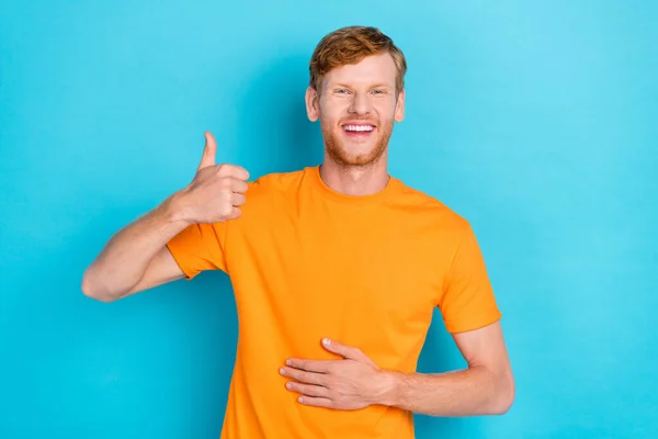 Photo of good ginger hair guy thumb up wear orange t-shirt isolated on vivid blue color background.