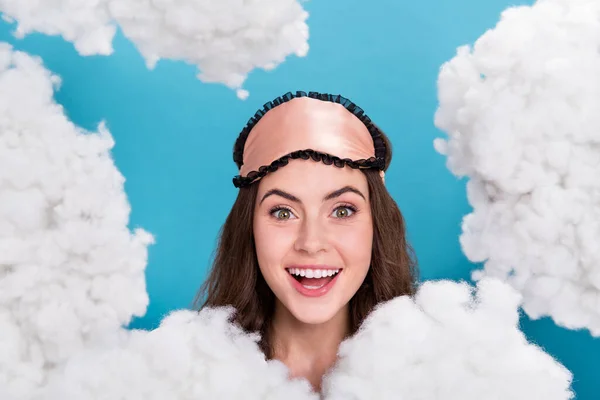 Photo of pretty excited lady wear pink pajama mask looking through fluffy clouds isolated blue color background.