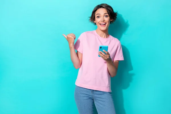 Photo of impressed bob hair young lady hold telephone index promo wear pink t-shirt jeans isolated on turquoise color background.