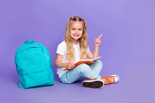 Full length photo of little pupil girl ponytails empty space homework backpack wear trendy white look isolated on purple color background.