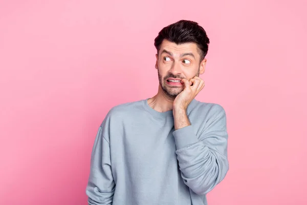 Photo of nervous anxious person biting finger nail look empty space isolated on pink color background.