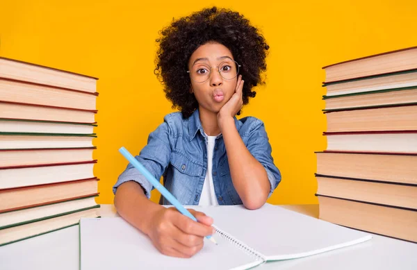 Portrait of attractive trendy cheery funny teen girl writing domestic work pout lips maths isolated over bright yellow color background.