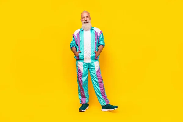 Full body portrait of cheerful aged man put hands pockets wear condensed milk tin color sport suit isolated on yellow background.