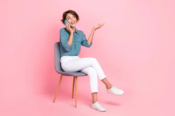 Photo of positive lady sit chair look empty space share news sale cool offer recommend device gadget isolated on pink color background.