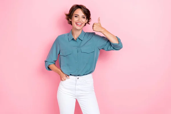 Portrait photo of young adorable pretty cute nice woman wear blue shirt white pants showing thumb up nice job veneers done isolated on pink color background.