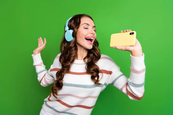 Photo of pretty funky lady wear striped sweater earphones singing songs modern device isolated green color background.