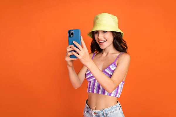 Photo of brunette pretty lady shoot photo wear hat top isolated on orange color background.