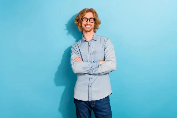 Portrait of cheerful nice young man crossed hands toothy beaming smile isolated on blue color background.