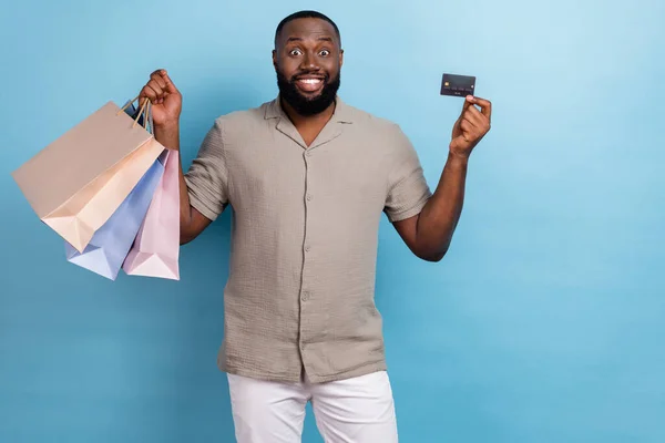 Photo of cheerful excited person hold packages plastic debit card isolated on blue color background.