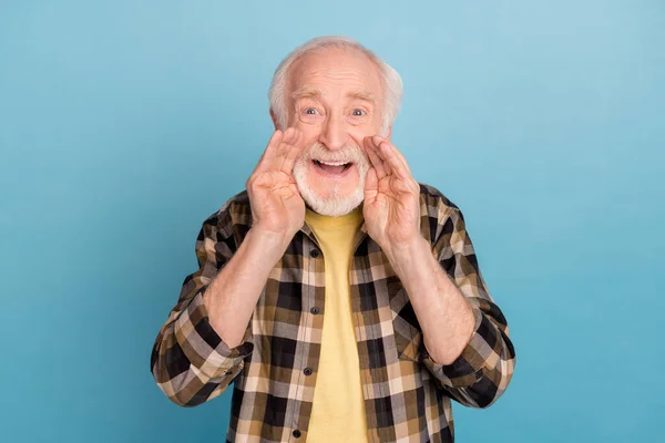 Photo of sweet excited man pensioner dressed checkered shirt arms mouth telling secret isolated blue color background.