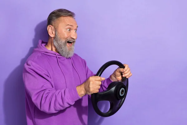 引退したハンサムな感銘を見て興奮男は紫色の色の背景に隔離ステアリングホイールを保持紫色のセーターを身に着けて — ストック写真