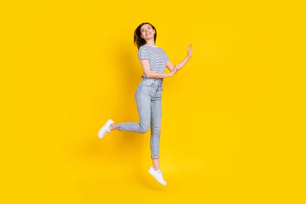 可愛い若い女性のフルサイズの写真は空のジャンプ感じるフリー服トレンディーなストライプの服は黄色の色の背景に孤立 — ストック写真