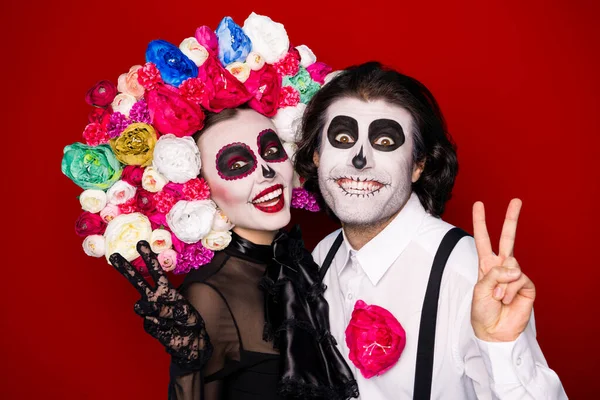Photo of scary creepy couple man lady cuddle show v-sign make message picture living succesors wear black dress death costume mask rose headband suspender isolated red color background.