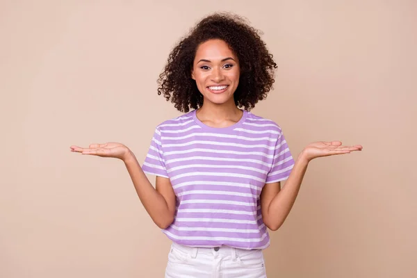 写真の光沢のある愛らしい女の子の服を着て紫Tシャツ示す腕スケール空のスペース孤立ベージュ色の背景 — ストック写真