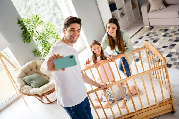 Portrait of cheerful friendly people take selfie record video sleeping toddler crib free time indoors.