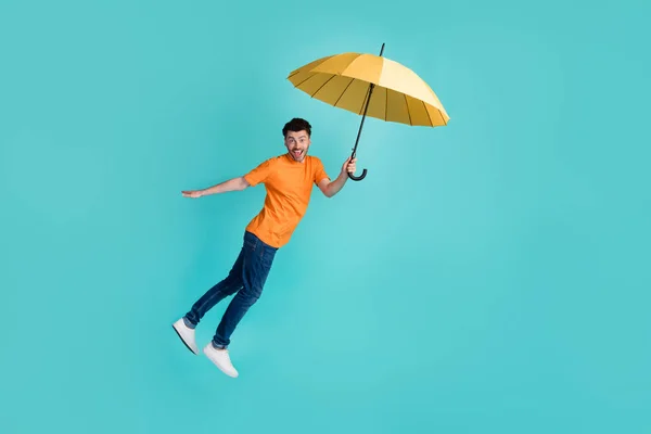 英俊的男演员喜剧演员抓拍到阳伞的全长照片想象一下在青色背景下被隔绝的飞舞风吹拂 — 图库照片