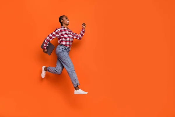 기사보기 에너지가 넘치는 소녀가 뛰어오르는 주황색 배경에 고립된 공간으로 보인다 — 스톡 사진