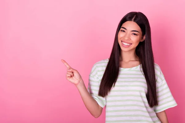 Portrait of pretty positive filipino girl toothy smile indicate finger empty space isolated on pink color background.