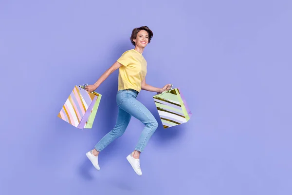 Full body photo of excited crazy lady hold packages jump rush hurry isolated on violet color background.