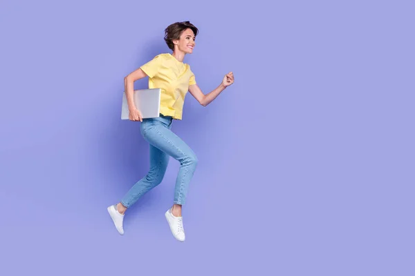 活泼开朗的女士拿着上网本在紫罗兰色背景下独立奔跑的全身像照片 — 图库照片