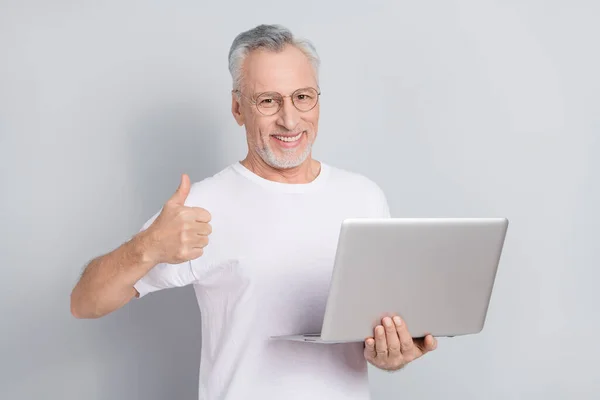 Portrait of satisfied cheerful person show thumb up hold wireless netbook isolated on grey color background.