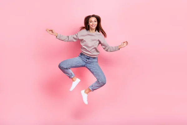 心满意足的女士跳跃的全身照片有着良好的心情 与粉色背景隔离 — 图库照片