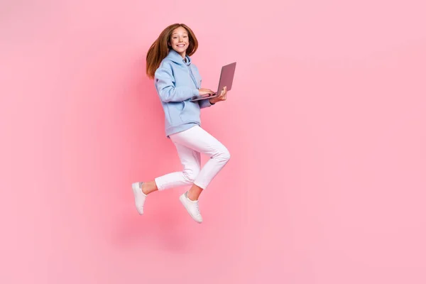 여자가 점프하는 모습의 사진은 분홍빛 배경에 넷북을 — 스톡 사진