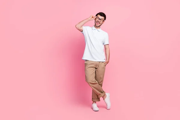 Full length photo of positive man wear fashionable clothes hand pocket touch spectacles stand empty space isolated on pink color background.