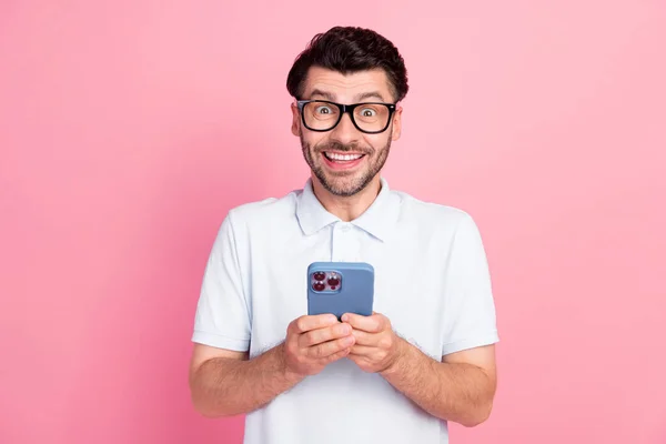 肯定的な素敵な男の写真は流行の衣装を着て電話を楽しむピンクの色の背景に隔離された現代的なデバイスガジェット — ストック写真