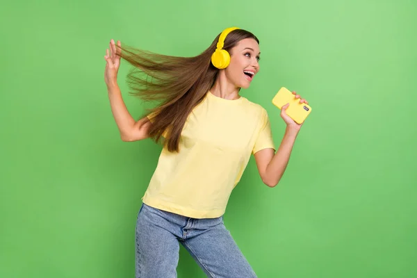 Photo of positive charming lady look empty space hand hold trendy modern telephone nice yellow accessory isolated on green color background.