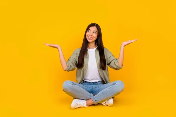 stock image Full length portrait of pretty positive lady look interested hands demonstrate empty space isolated on yellow color background.