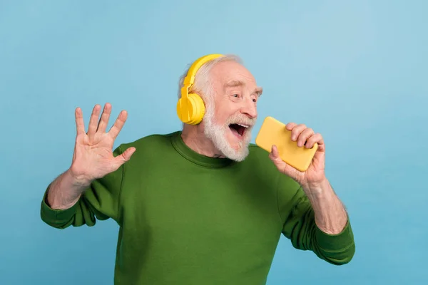 Portrait of excited crazy person hold telephone singing voice recording application isolated on blue color background.